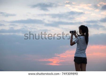 Woman tourist photographer with camera on top of mountain at sunset 