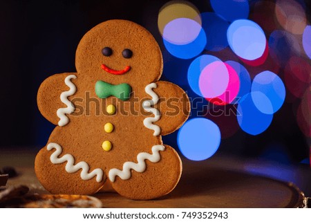 Composition with tasty smiling gingerbread man and Christmas lights on blurred background