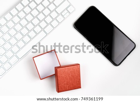 Top view, Modern workplace with smart phone and Gift Box with keyboard placed on a pastel white background. Copy space suitable for use in graphics.