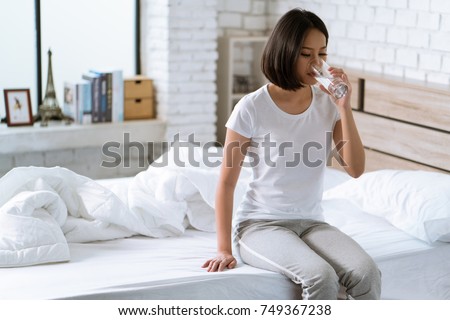 Asian woman drinks water after waking up in the morning. Royalty-Free Stock Photo #749367238
