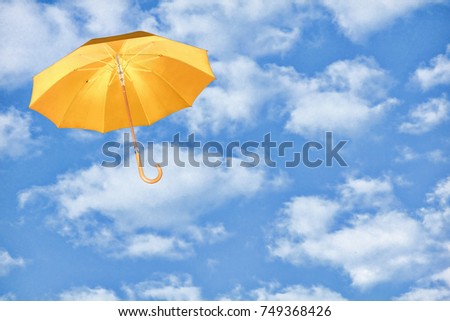 Mary Poppins Umbrella.Yellow umbrella flies in sky against of white clouds.Wind of change concept. Royalty-Free Stock Photo #749368426