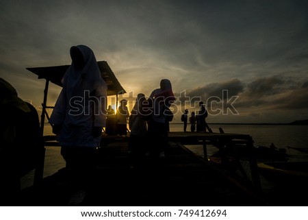 Silhouette of kids on their school uniform go to school by a motorboat in the morning at Pulau Pababang, Semporna, Sabah, Borneo, Malaysia.