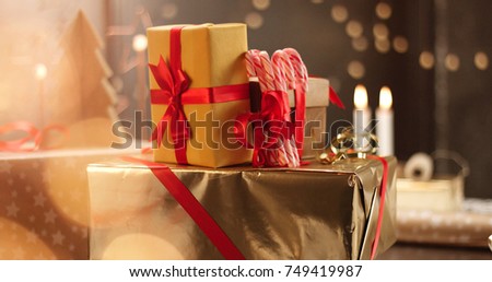 Beautifully wrapped Christmas presents on the background of stylish decorations and lights in warm golden and red tones