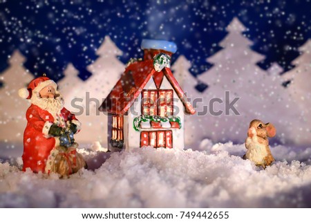 Fabulous new year's picture with Santa and a Bunny next to the house on a winter night in the snow