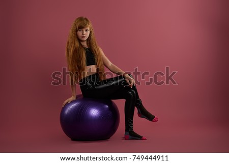 Little red-haired sportswoman posing on purple ball