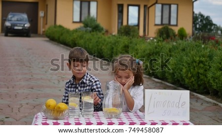 Two little kids are selling lemonade at a homemade lemonade stand on a sunny day with a price sign for an entrepreneur concept