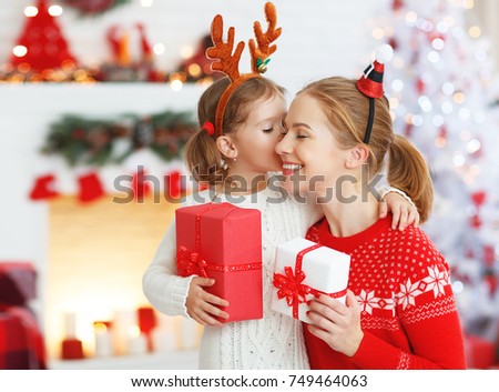 happy family mother and daughter giving christmas gift and embracing