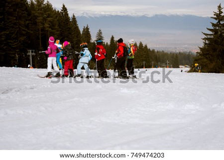 Large group of toddlers standing in a row and learning to ski on snow mountain.