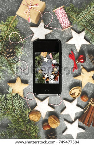 Close-up of smartphone with picture of Christmas decoration on blurred festive background.