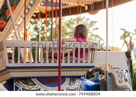Child on a carousel at a carnival or festival at sunset. Decorative ornate elephant, animals at an amusement park.
