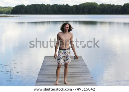 Portrait of a man standing at an old wooden jetty at a lake