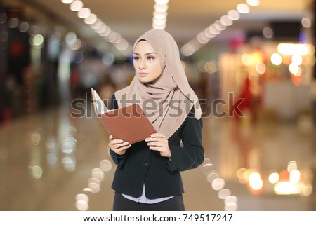 Portrait of young Muslim women dressed in office and holding a book