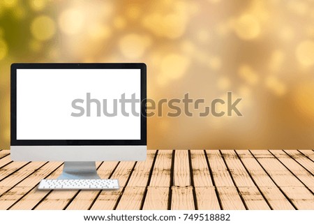 Modern computer blank monitor screen on wooden table with golden bokeh blurred background