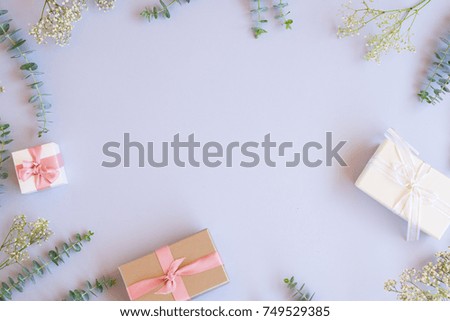 Green leaves with present gift boxes on blue table from above with copy space, flat lay frame