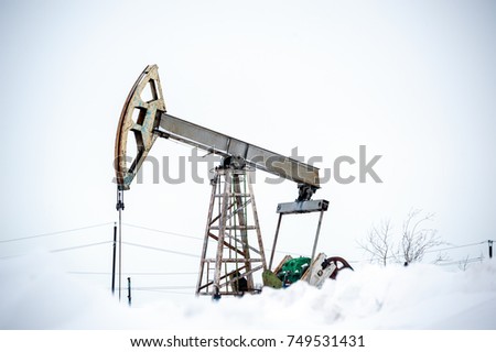 Horizontal view of a oil pump jack on a oilfield industrial site in severe winter. Crude oil production.