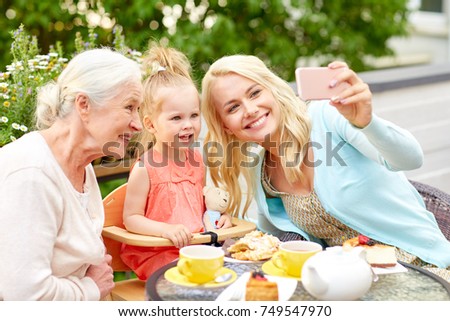 family, generation and people concept - happy mother, daughter and grandmother taking selfie by smartphone at cafe or restaurant terrace