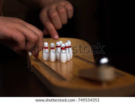 
Children's hands throw out pins for playing mini bowling in soft focus