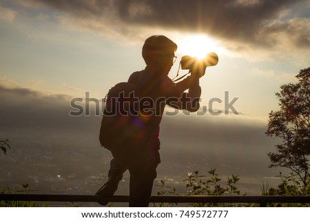 silhouette of Stock Photo contributors tourism explore forests in Asia. hand holding camera holding pro digital camera with telephoto lens. Photo Stock career. Stock Photo contributors Concept