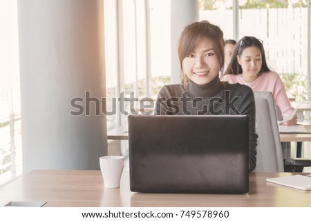 Asian business woman who sitting work by notebook in feeling happy at the office with daylight from window and blur garden background.