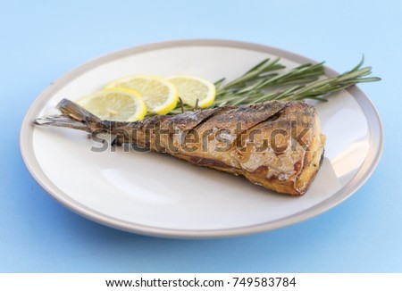 Top view Fried Mackerel  with rosemary and slice of lemon on blue background