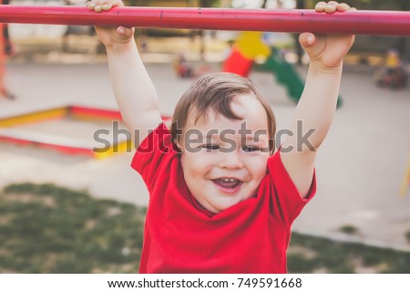portrait of cute little boy in red t-shirt playing and smiling on playground. concept of happy healthy child Royalty-Free Stock Photo #749591668