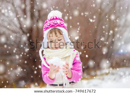 A child plays in the snow in the winter. Selective focus.