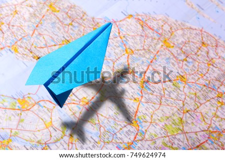 Paper plane above the map, a shadow like a real airplane. Planning for a trip around the world on vacation.