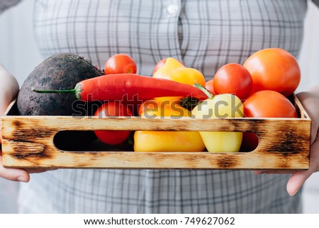 Senior woman holding a box with vegetables in hands