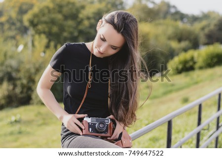Young happy female photographer walks in the Park with retro camera.