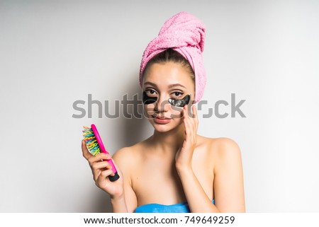 young cute girl with clean skin, with a pink towel on her head holding a comb, looking into the camera