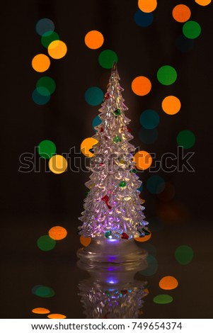 Glowing Christmas tree on black background with colored lights. The silhouette of the tree with the reflection. Beautiful bokeh. For design.