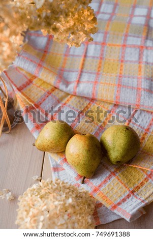 Autumn composition. Dried hydrangea, pears on a yellow linen napkin. On a wooden background.