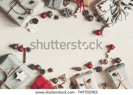 christmas flat lay. present boxes with ornaments and pine cones anise on white wooden background top view, space for text. stylish wrapped gifts frame. seasonal greetings card. happy holidays