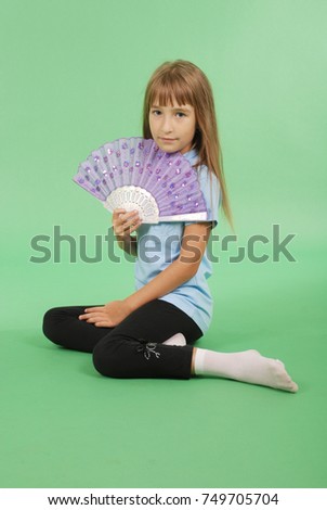Young girl with light hair holding pink lace fan in hand isolated on green background