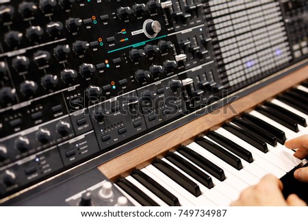 A musician at the keyboard of modern analog synthesizer. Selective focus.