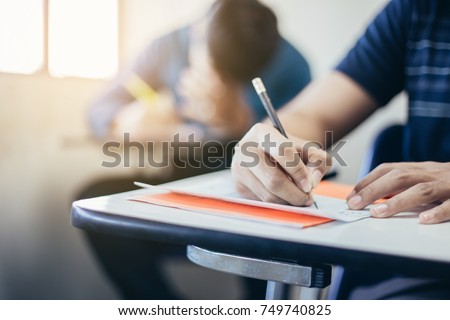 soft focus.high school or university student holding pencil writing on paper answer sheet.sitting on lecture chair taking final exam attending in examination room or classroom.student in casual. Royalty-Free Stock Photo #749740825