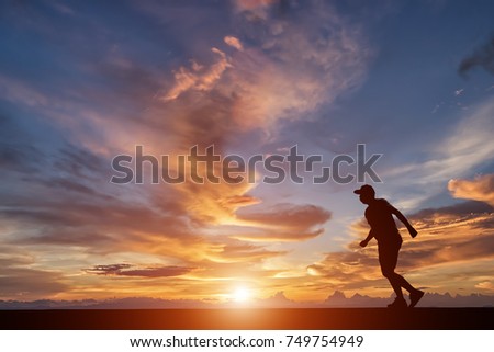 Silhouette of happy people running on street in sunset.