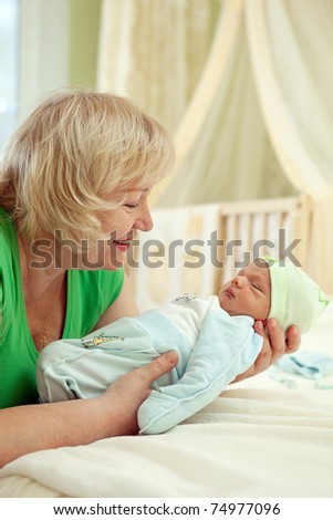 Happy mature woman holding her newborn grandson