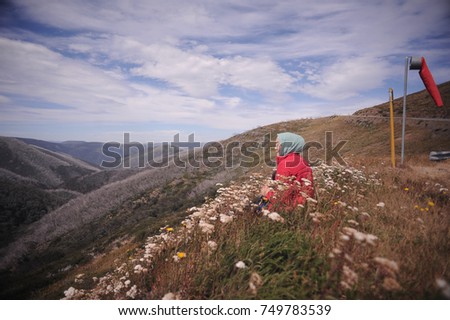 Young woman seat on the grass on the top of the mountain with beautiful mountain scenery.Summer activity.
