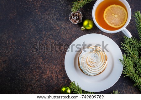 Delicious Christmas Dessert. Lemon tartlet tart with with meringue and cup of hot chocolate with marshmallow on dark stone concrete table background. Christmas Holiday Decoration. Top view, copy space