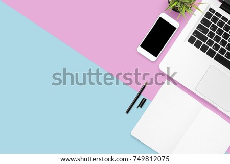 Pastel pink and blue office desk table with laptop computer, smartphone with blank screen and supplies. Top view with copy space, flat lay.