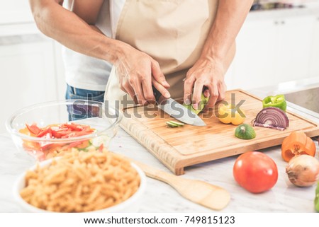 Hands of couple or lovers cooking  and slicing vegetables with knife together.  Man teaching woman to cook. Happiness in holiday and honeymoon concept