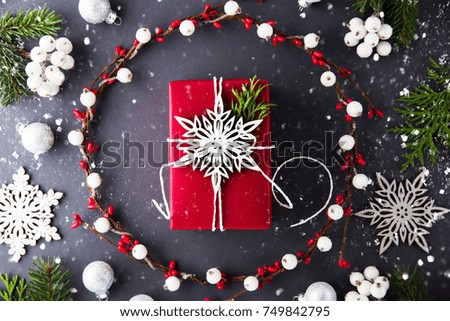 Frame with christmas wreath and red gift box on dark background top view. Merry christmas greeting card. Winter xmas holiday theme. Happy New Year. Flat lay.