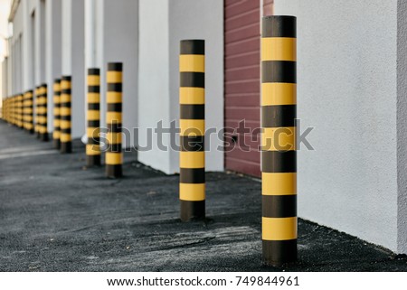 Closeup of yellow and black steel bollards that restrict movement of cars