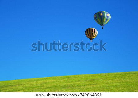 Hot air balloon over green field and blue sky
