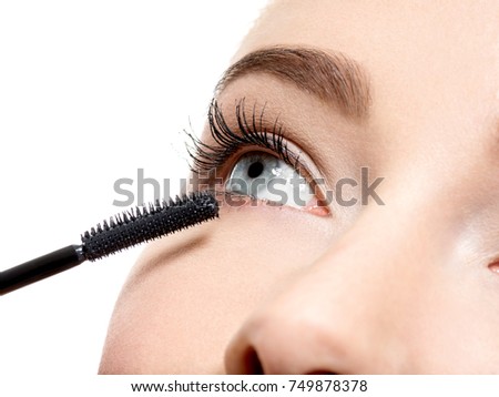 Macro shot of a women eye with long black eyelashes and makeup brush  -  studio photo