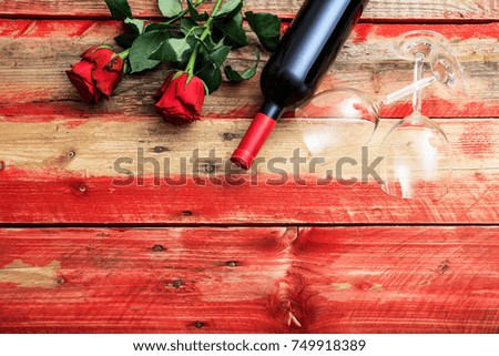 Valentines day concept. Red wine bottle, glasses and roses on wooden background