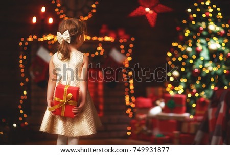 happy child girl back with christmas gift at evening home
