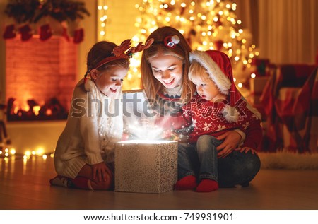 Merry Christmas! family mother and children with magic gift at home near  Christmas tree and fireplace
