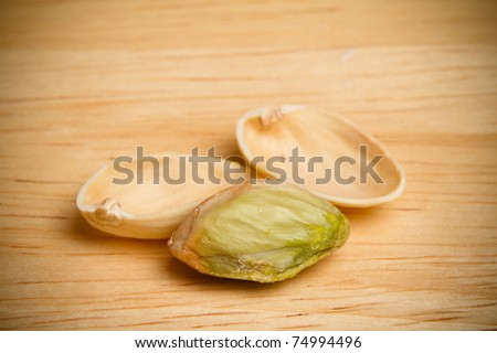 This is a close up shot of an open pistachio. Shot with a shallow depth of field on a wooden surface with vignetting.